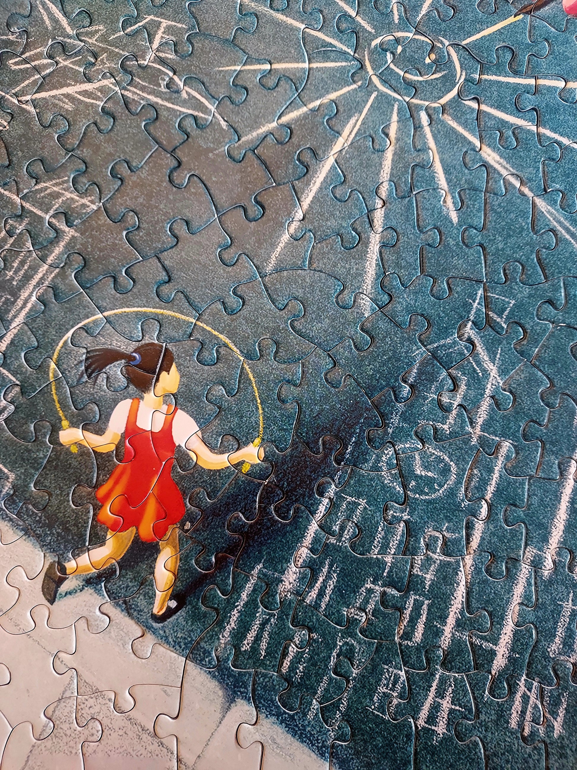 A area of a completed jigsaw puzzle that includes the illustrate image of a girl with a moving pony tail skipping rope near chalk drawings.