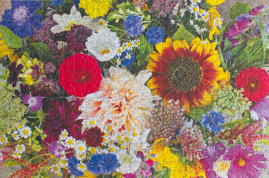 A completed jigsaw puzzle showing a bright photograph of many types of flowers.