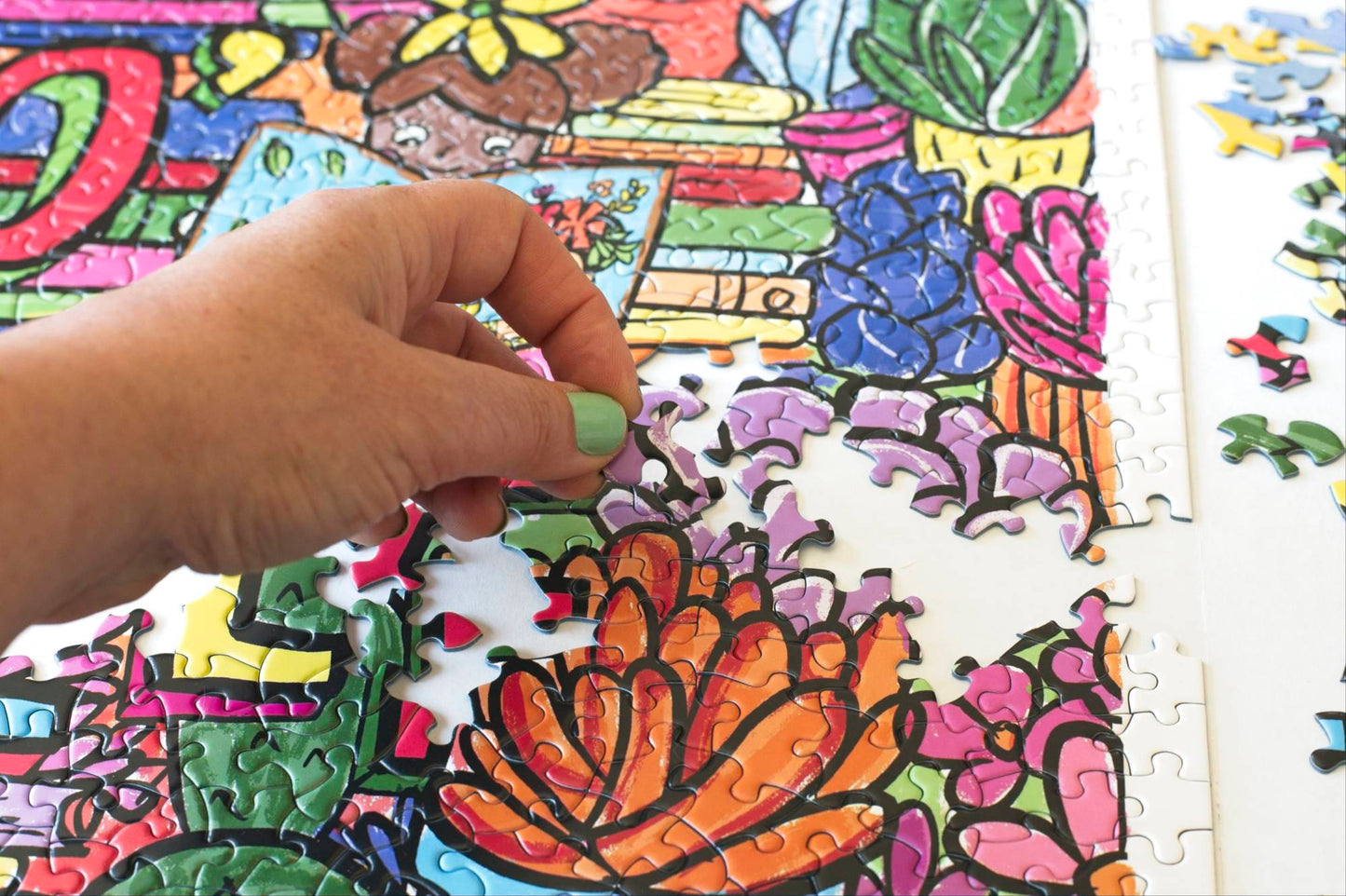 A photo of a hand putting a jigsaw puzzle piece into place on a colorful partially completed puzzle.