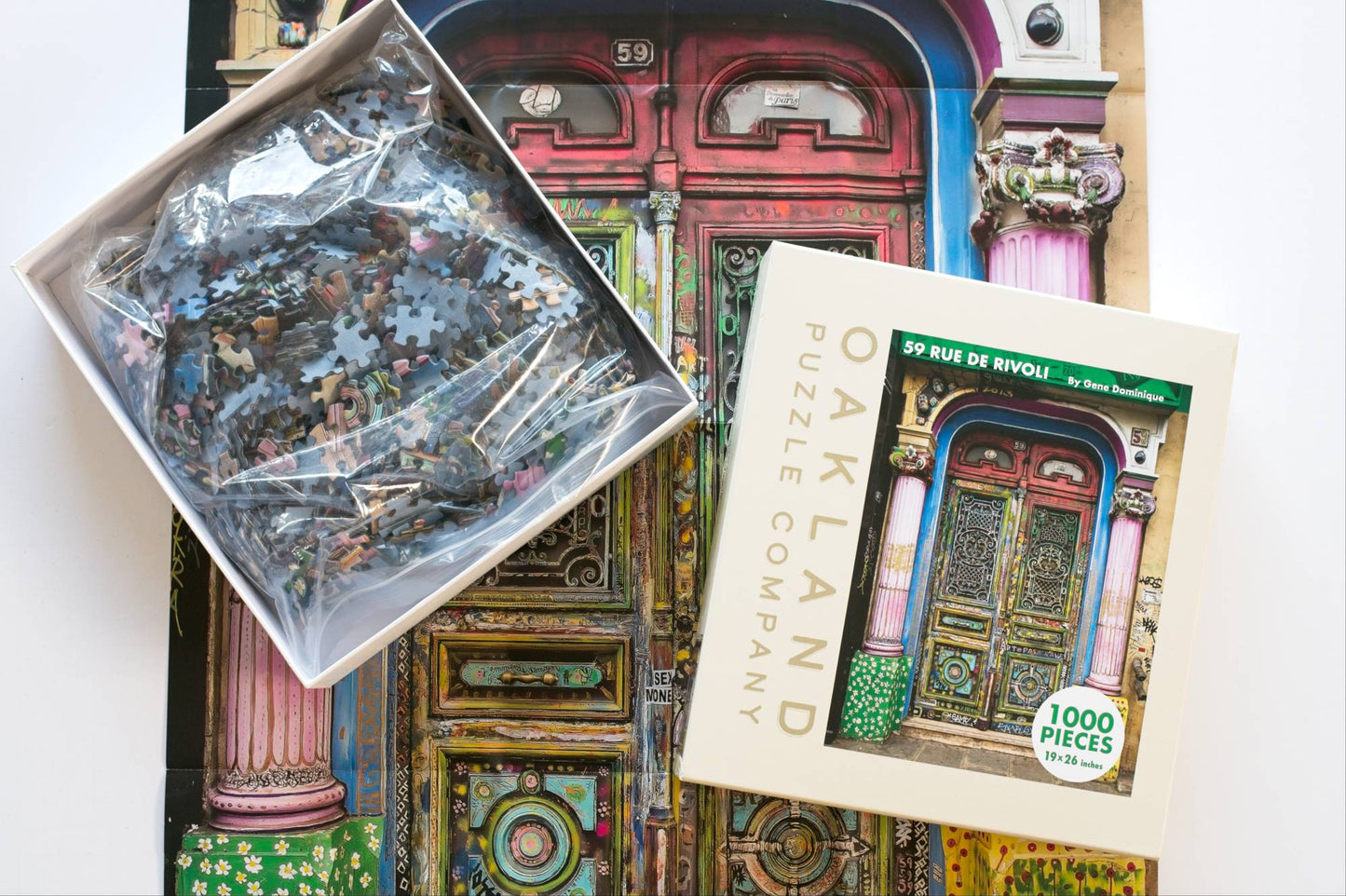 A jigsaw puzzle box open on a reference poster of a colorful doorway. The bottom of the box shows a resealable plastic bag filled with pieces the top has Oakland Puzzle Company.