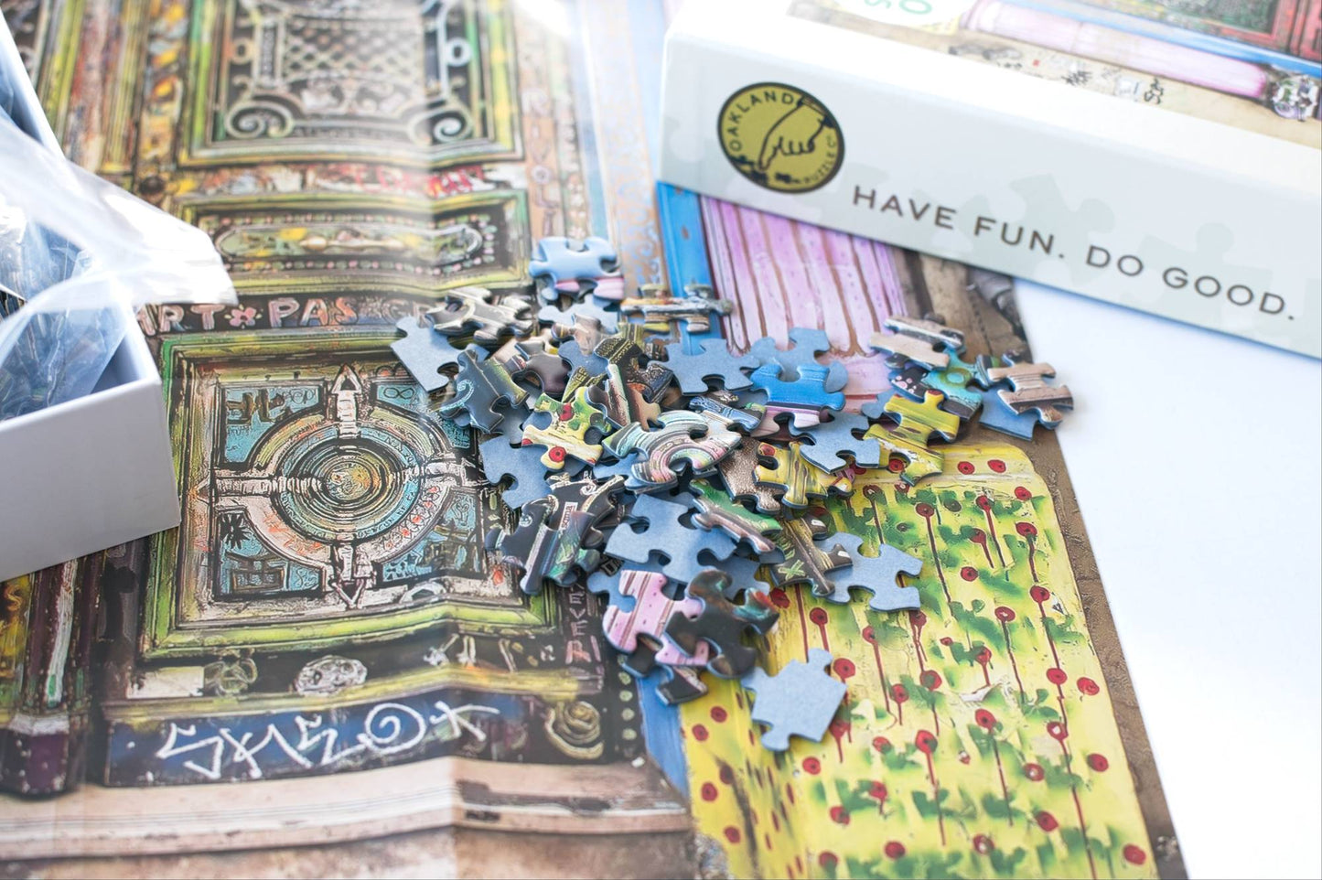 Puzzle pieces scattered on a colorful image with an open box featuring a visible brand logo.