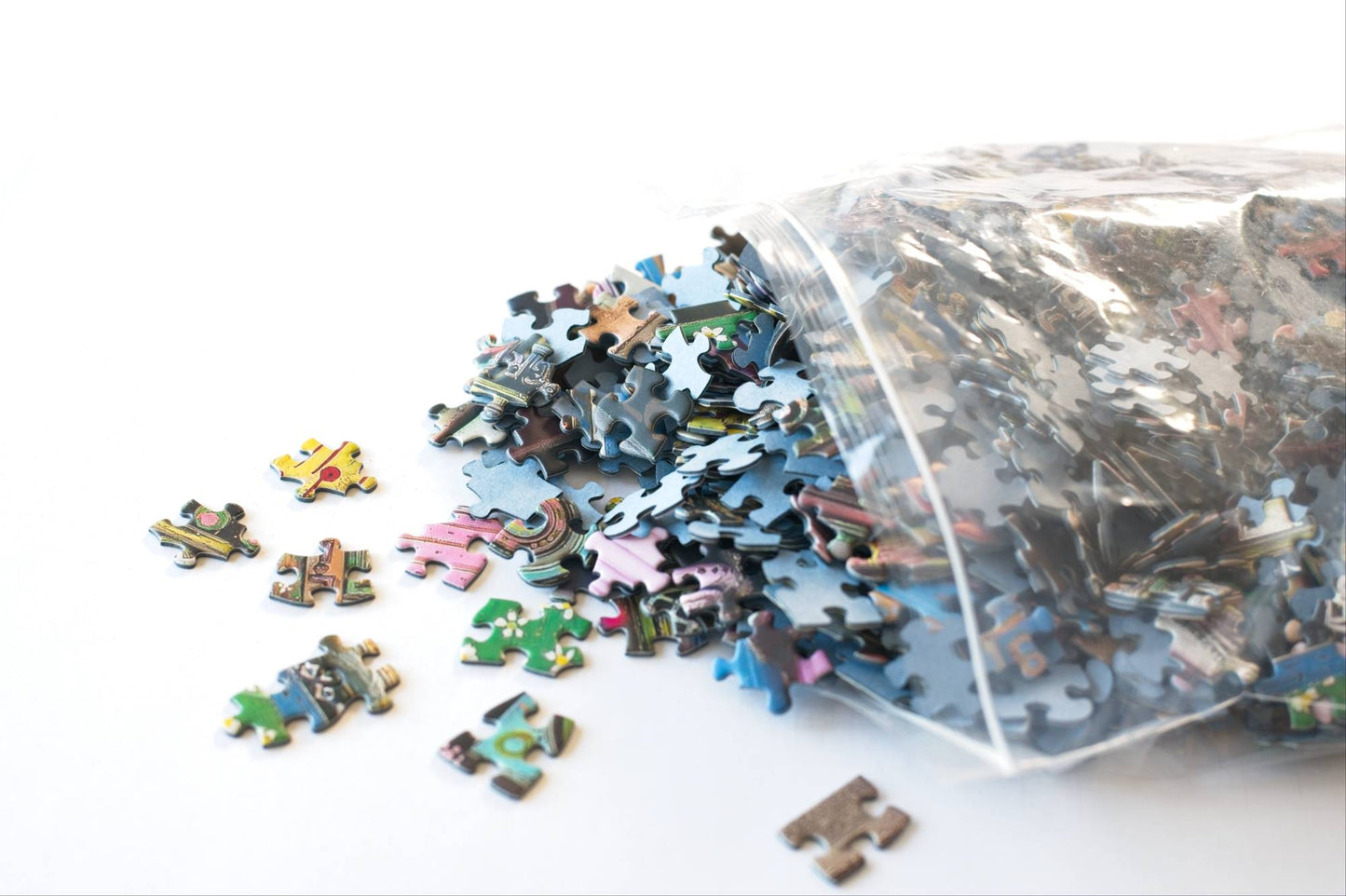 Pile of puzzle pieces spilling out of a resealable plastic bag on a white background