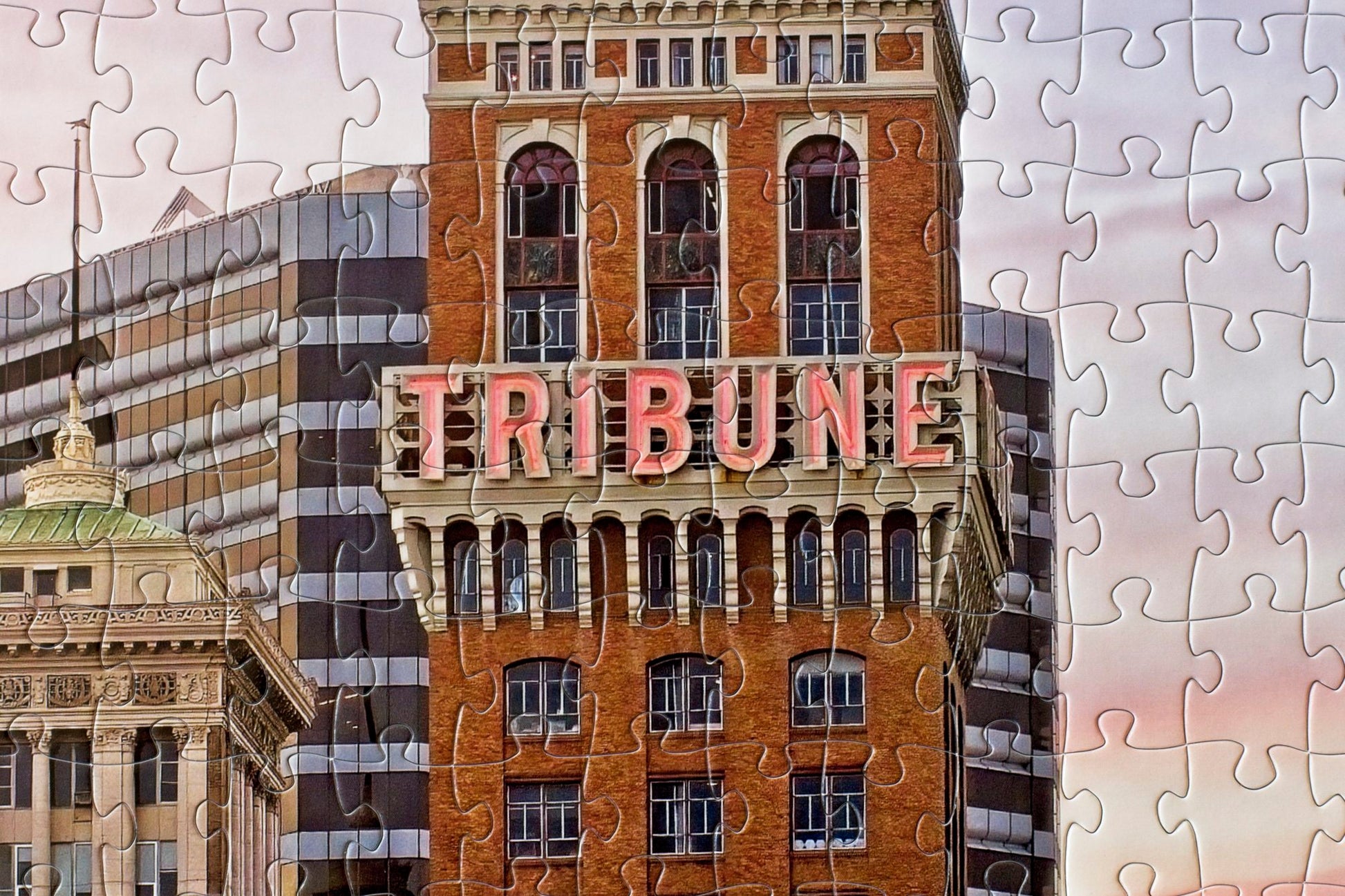 A close-up of the completed Tribune Tower jigsaw puzzle with the Tribune name centered in the image with a few other buildings and a purplish sky behind.