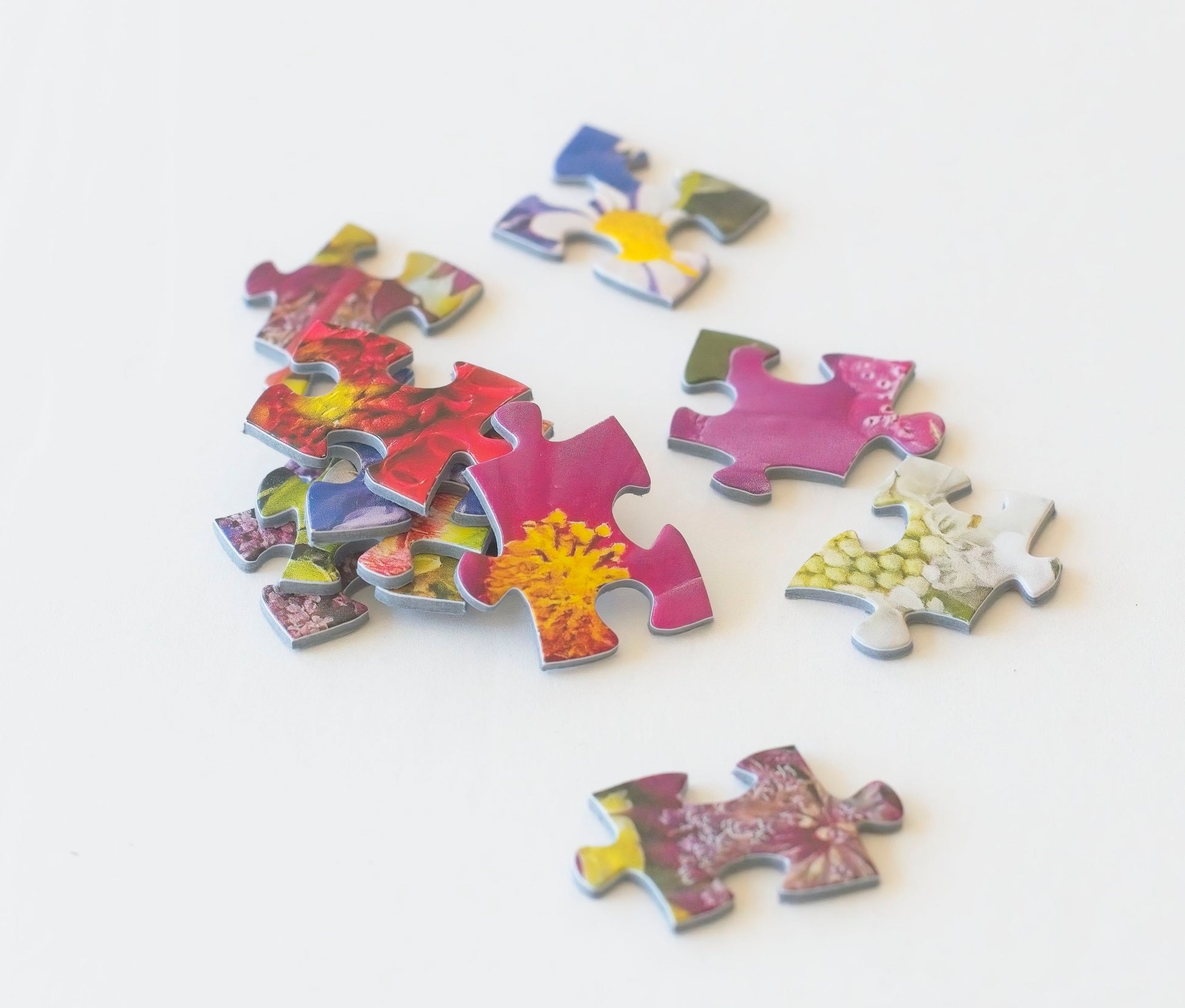 Bright puzzle pieces of flowers loosely stacked and scattered about.