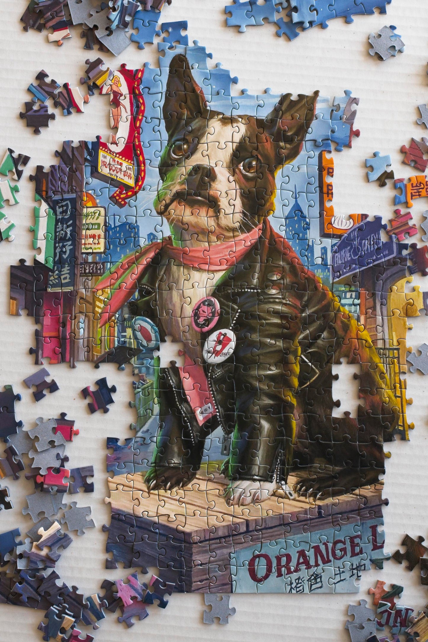 A partially completed puzzle centered on a Boston Terrier with other puzzle pieces scattered around