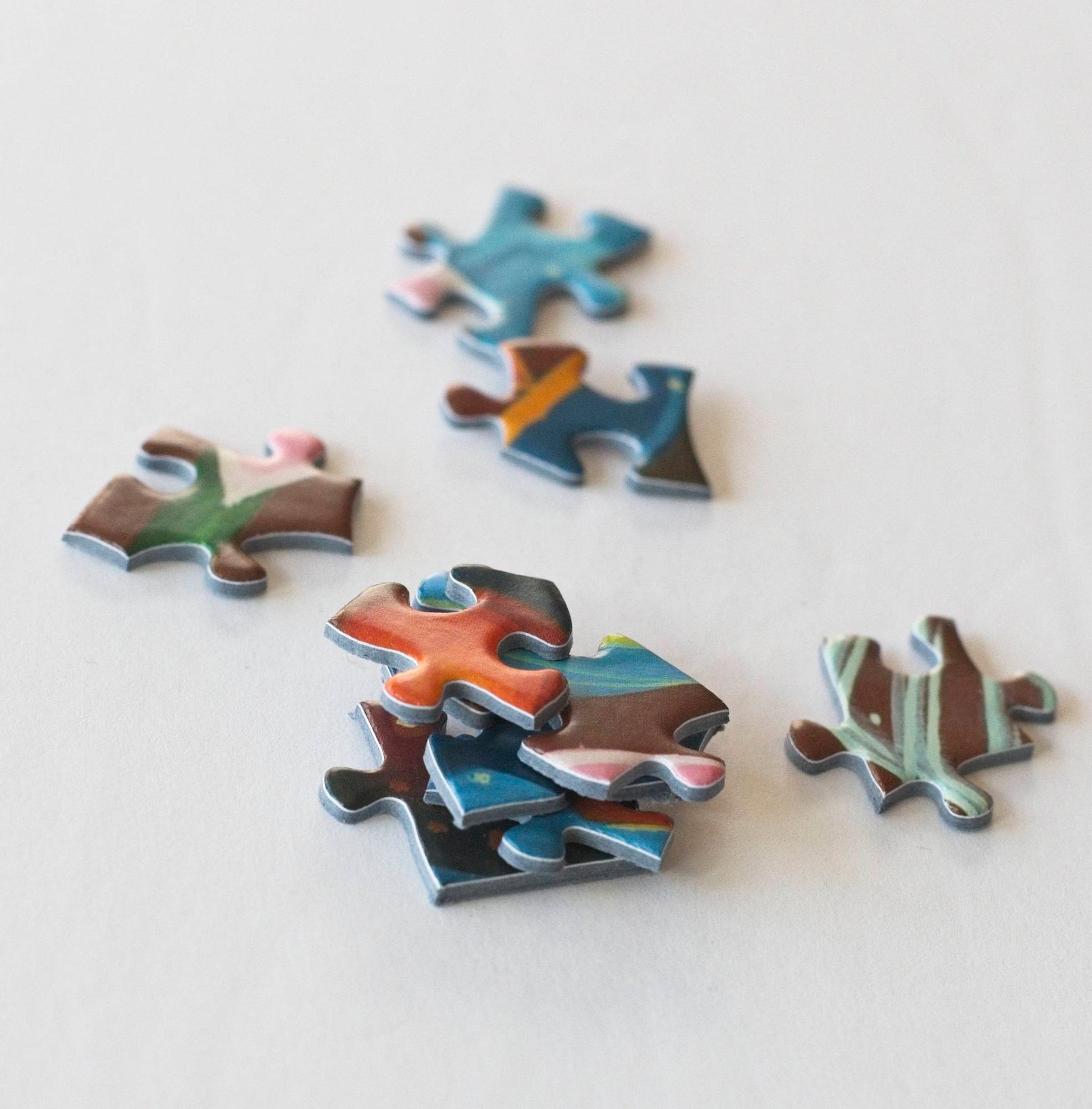 Colorful stacked randomly shaped puzzle pieces with a few puzzle pieces scattered around.