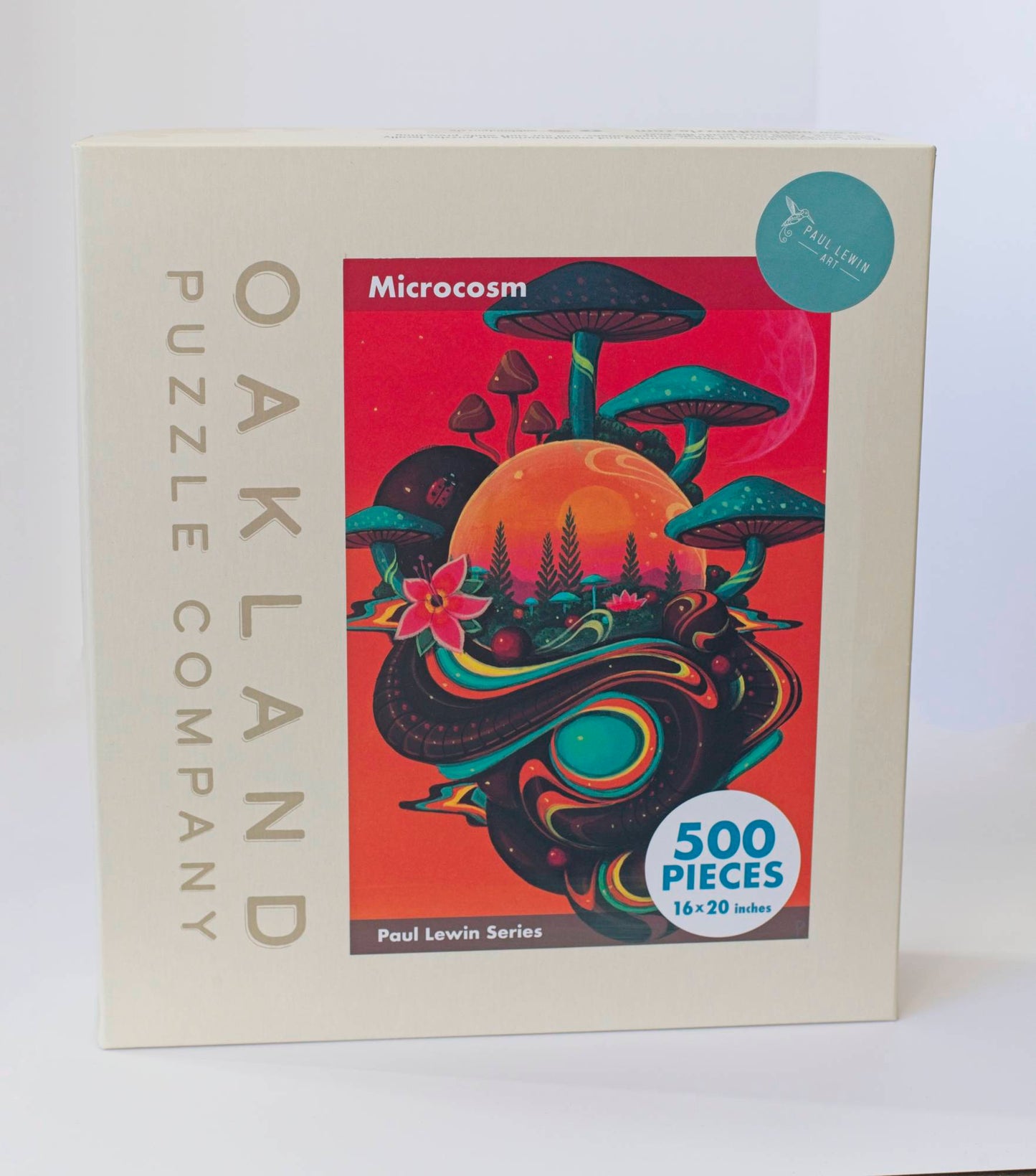 A box branded Oakland Puzzle Company with a colorful orange Afrofuturist image with mushrooms, flowers, and orbs titled Microcosm Paul Lewin Series