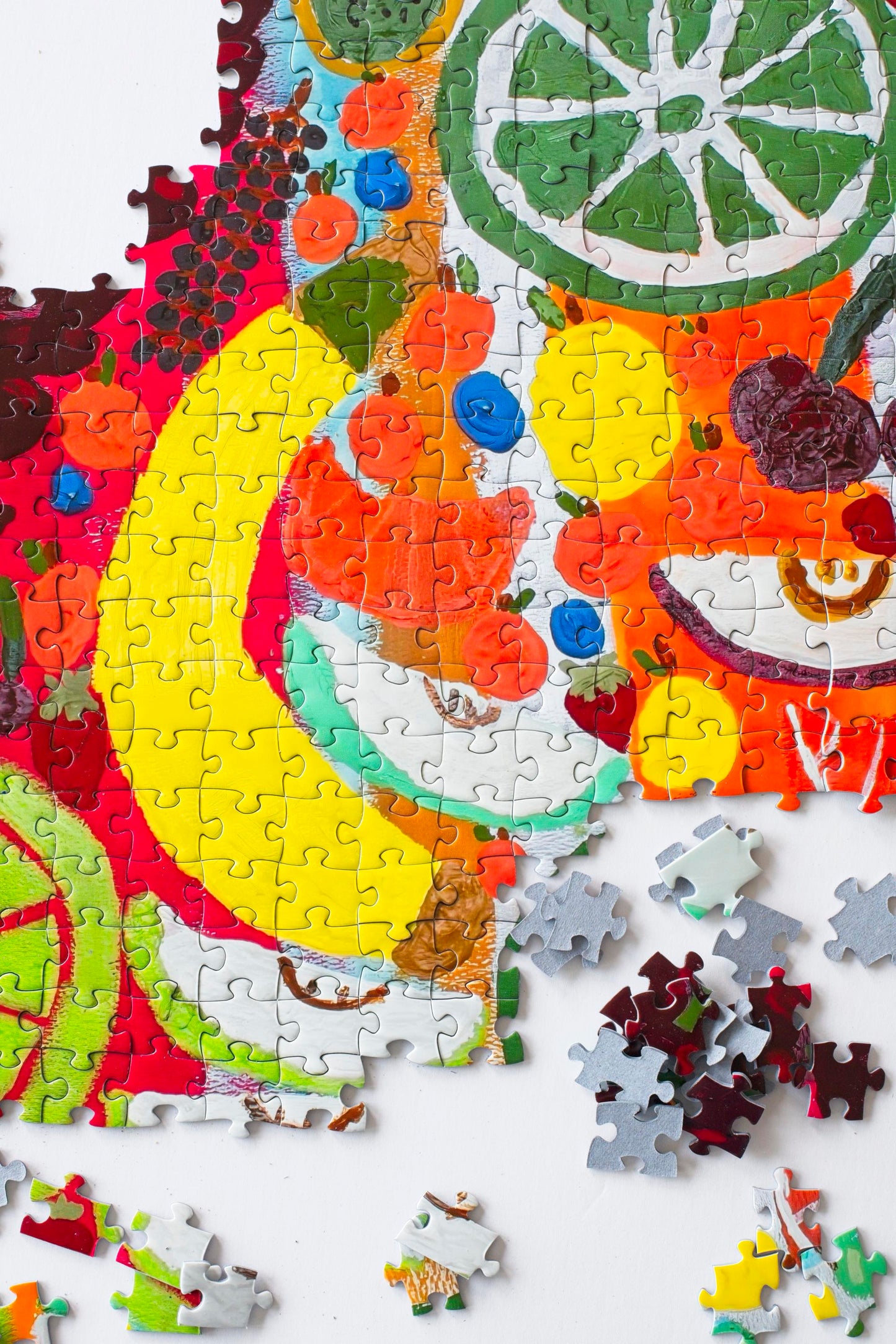 A partially assembled colorful jigsaw puzzle with a variety of fruit artistically rendered