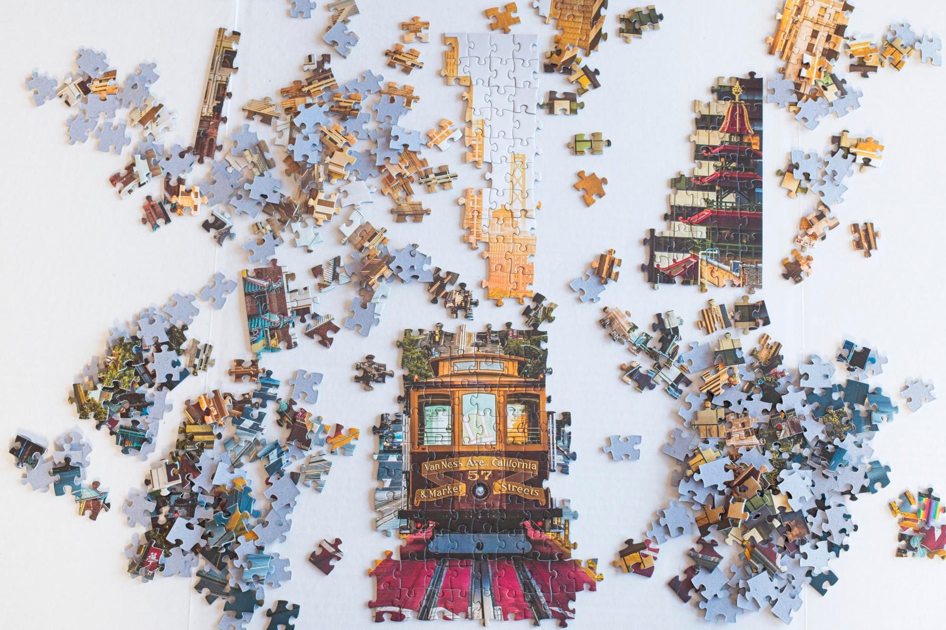 A variety of joined and strewn puzzle pieces showing a trolley, a building and the bridge