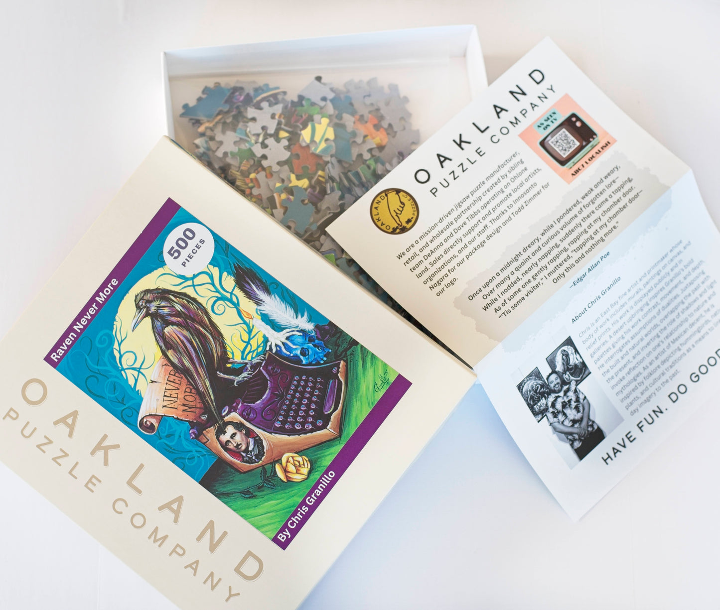 A box top branded Oakland Puzzle Company with the Raven Never More image featured on the front. Next to it is the opened box with a bag filled with puzzle pieces and a puzzle guide next to it.