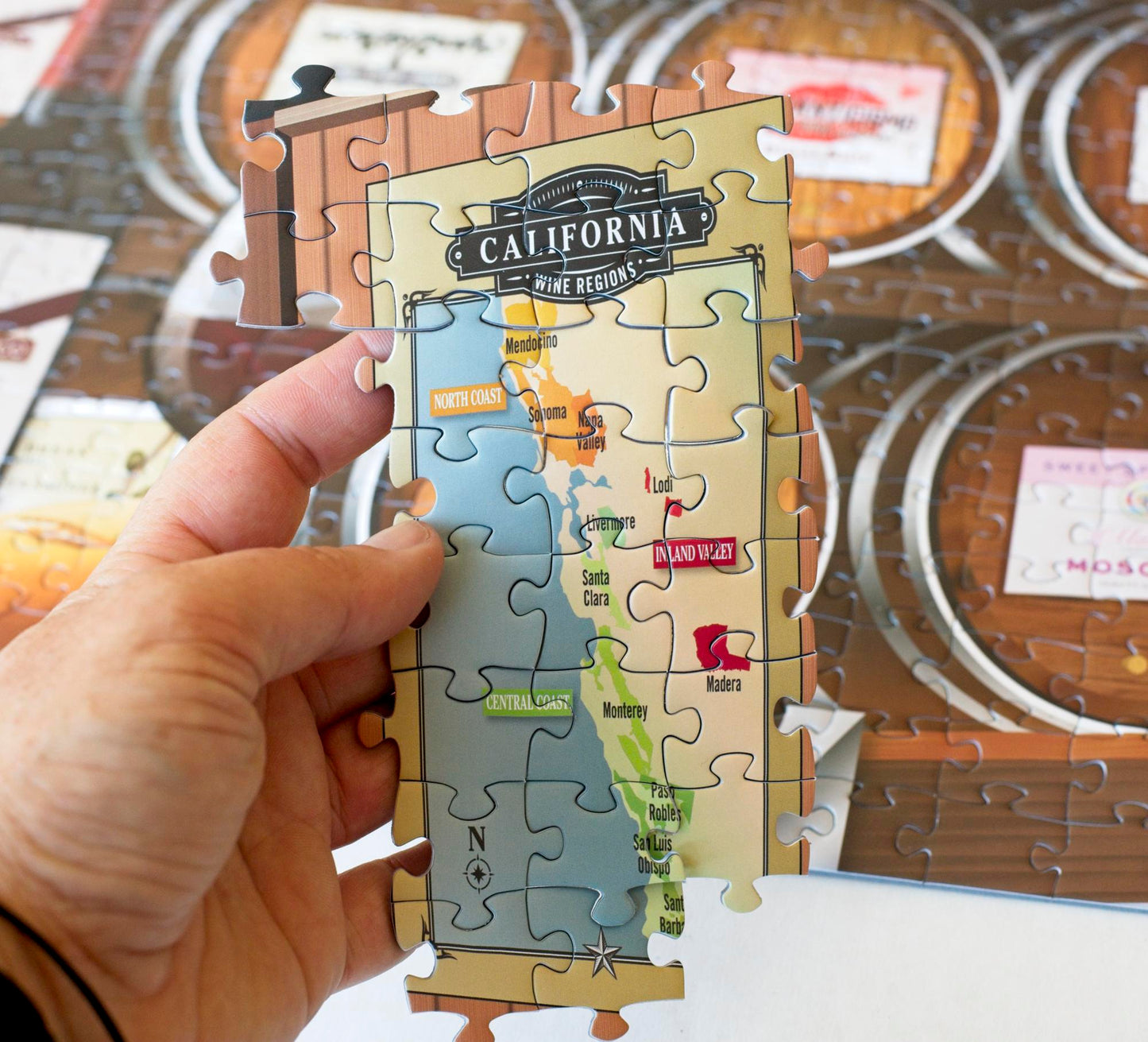 A hand holding a group of joined puzzle pieces showing a map labeled California Wine Regions