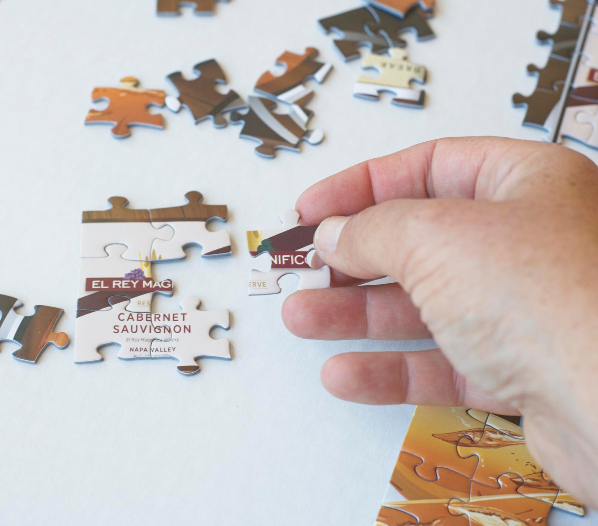 A hand ready to place a puzzle piece to add to the image of a wine label