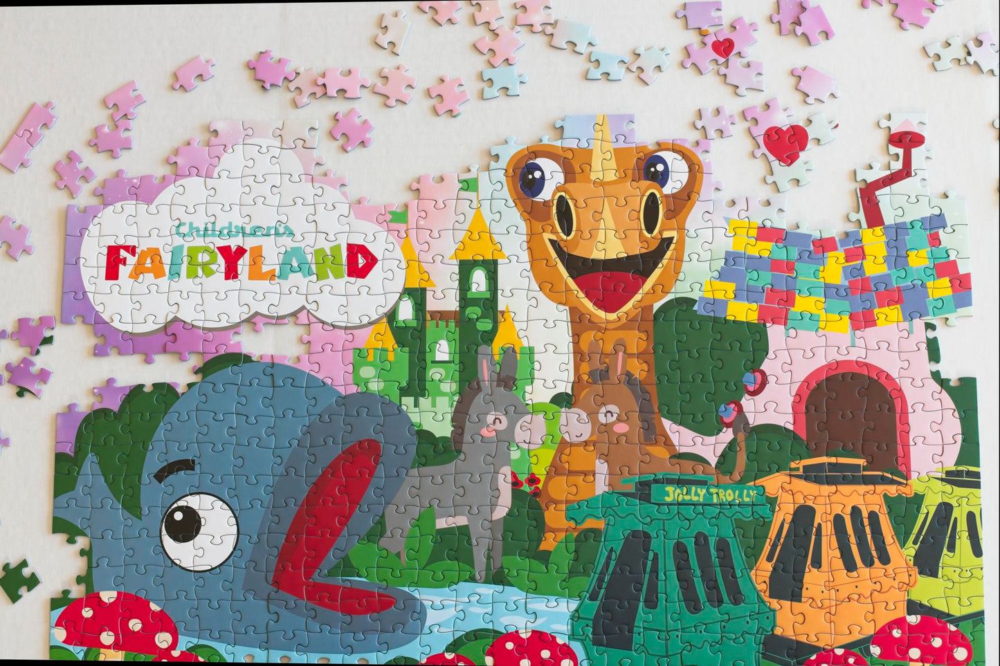 A mostly completed jigsaw puzzle of features at Children's Fairyland with pieces scattered above.