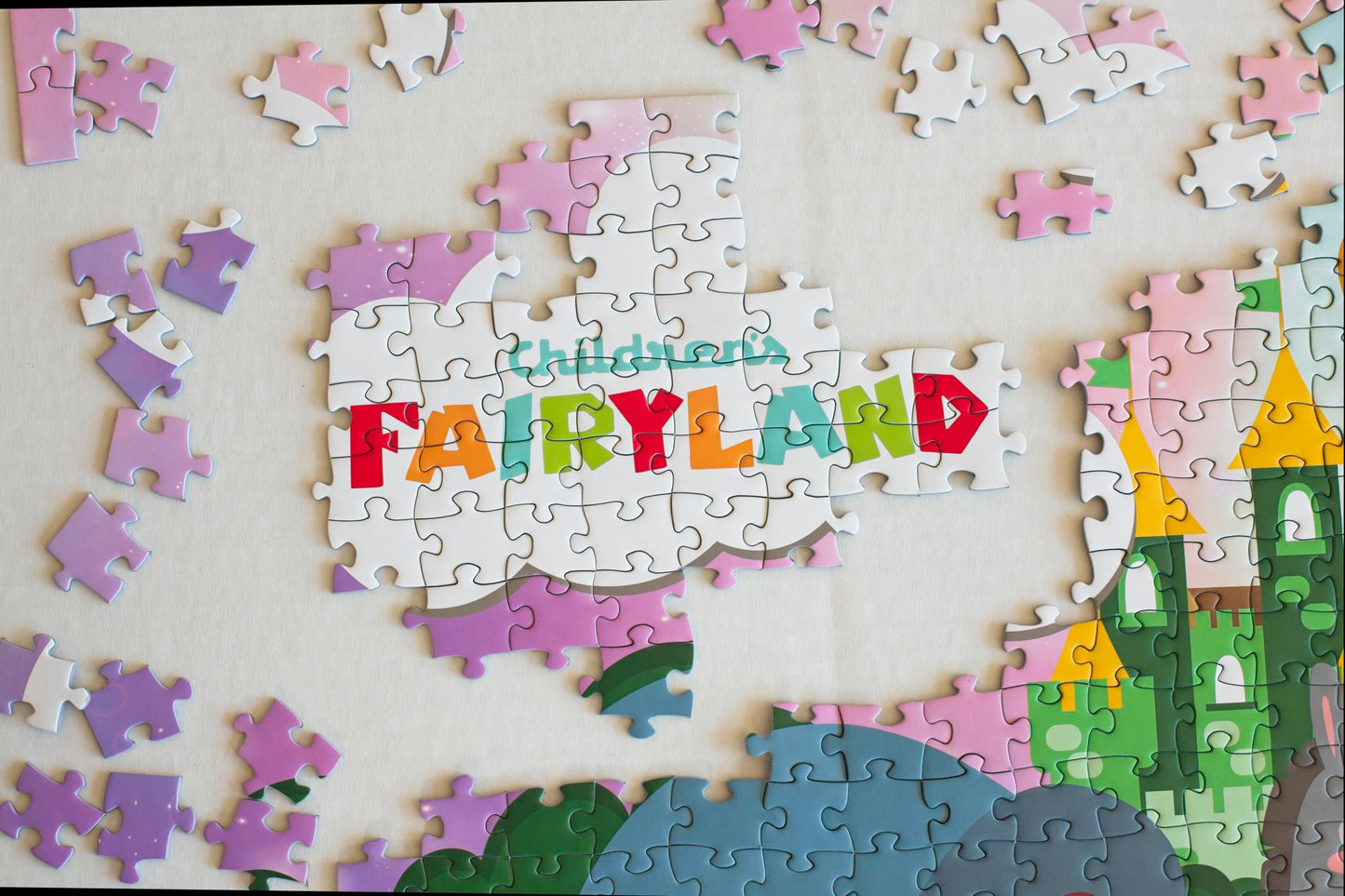 The Children's Fairyland logo displayed on puzzle pieces surrounded by loose pieces and an area of completed puzzle.