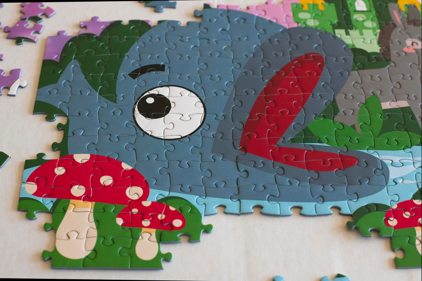 A close-up shot of Willy the Whale illustrated on an area of conjoined jigsaw puzzle pieces with bright mushrooms next to him.
