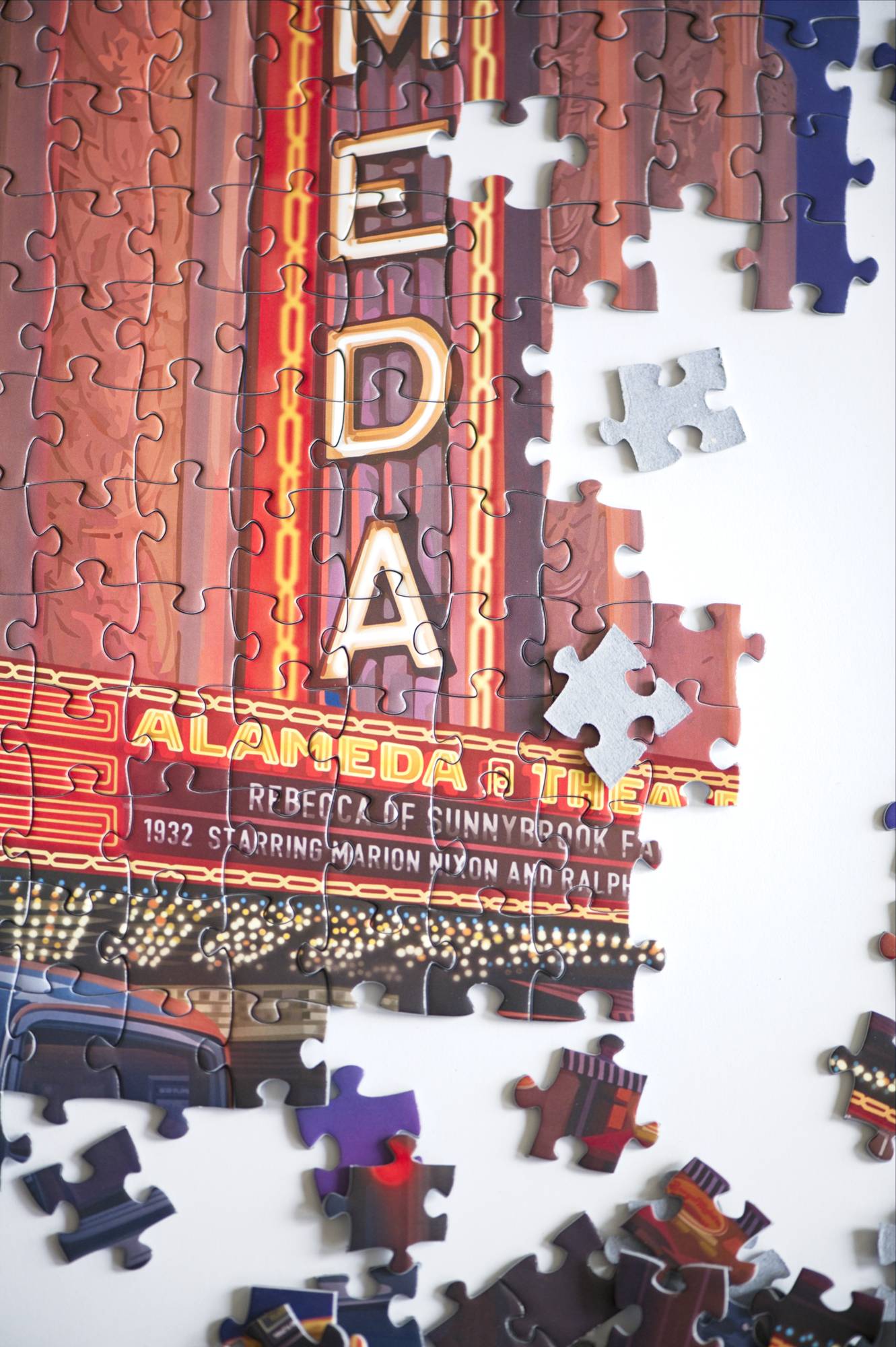 A close-up photo showing the marquee section of the partially assembled jigsaw puzzle with some scattered pieces around and some turned over showing blue board.