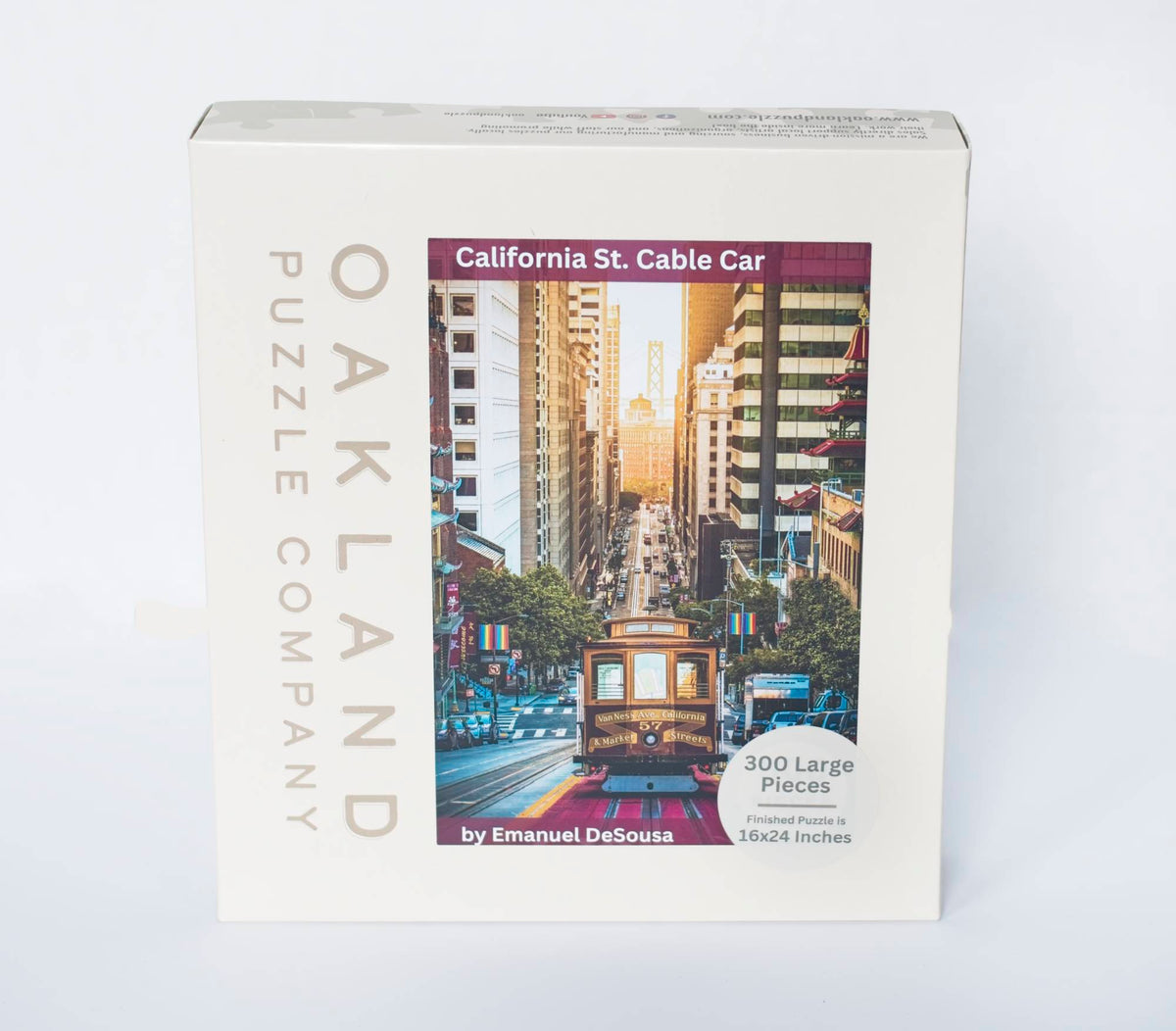 A jigsaw puzzle product box showing a photo of a San Francisco Cable Car scene with the Bay Bridge and sunrise in the background with Oakland Puzzle Company branding labeled 300 large size pieces