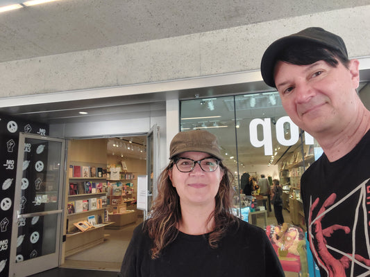 Two people smiling into the camera in front of the gift shop at Oakland Museum of California
