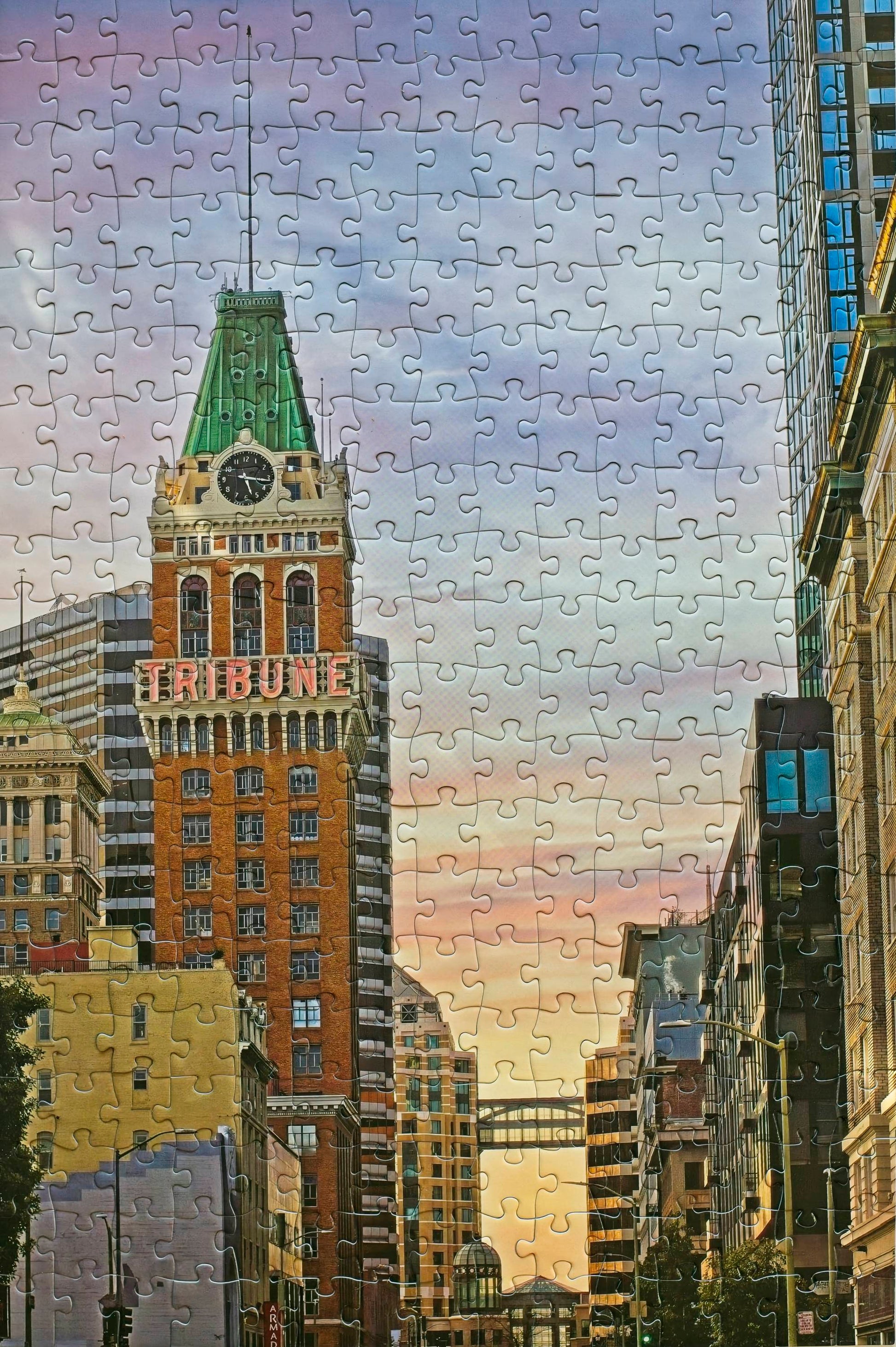 A photo of a completed jigsaw puzzle featuring Oakland's Tribune Tower with a  gradient sunset in the background