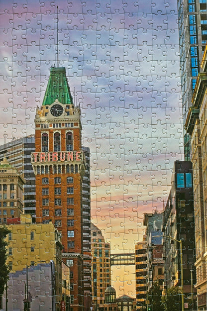A photo of a completed jigsaw puzzle featuring Oakland's Tribune Tower with a  gradient sunset in the background