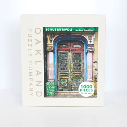Jigsaw puzzle box with colorful door design and 'Oakland Puzzle Company' branding.