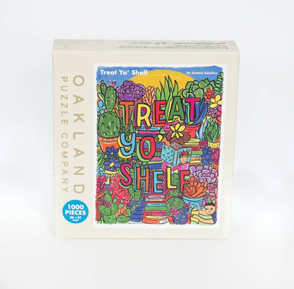 A photo of a beige box branded Oakland Puzzle Company with the Text Treat Yo' Shelf by Susana Sanchez at the top and 1000 Pieces  20x27 inches in a blue circle in the corner. The box features a brightly colored whimsical image.