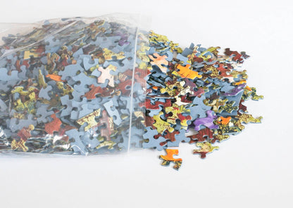 Colorful random cut jigsaw puzzle pieces spilling out of a resealable plastic bag.