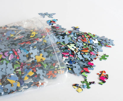 brightly colored random-cut puzzle pieces made from blue board spill out of a resealable plastic bag.