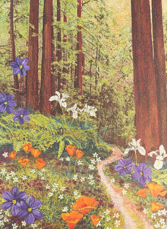 A photo of a completed random cut jigsaw puzzle featuring an image of redwood trees in golden light with flowers scattered around a forest path.