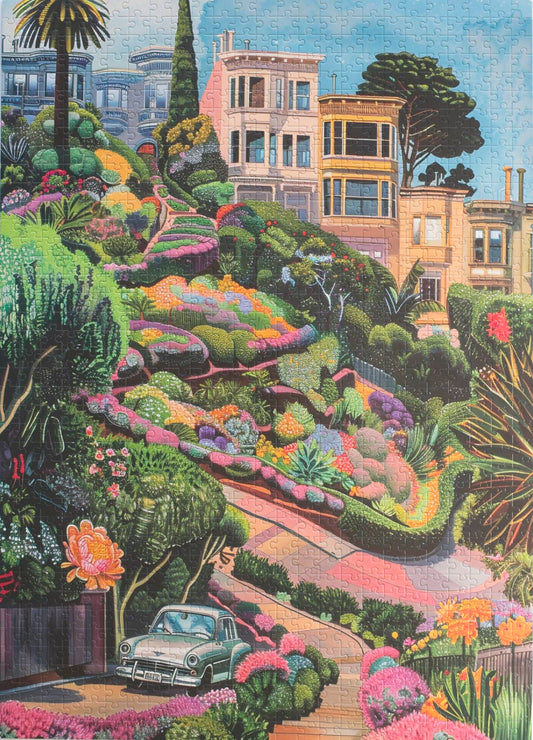 A photo of a completed jigsaw puzzle with traditionally cut pieces featuring a whimsical and colorfully rendered image of curvy Lombard Street with Victorian houses behind, a vintage car in the foreground, and a landscape dotted with flower all around.
