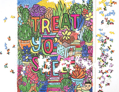 A nearly complete jigsaw puzzle with scattered pieces around the edges. A photo of a completed random-cut puzzle featuring a drawn image filled with colorful succulents and flowers and stacks of books. The words Treat Yo' Shelf are written in multi-colored block letters with shadows. In the center a child wearing pink reads a book with Frida Kahlo on he cover and another child wearing blue reads near the corner.  At the top appears to be a blue sky and giant sun.