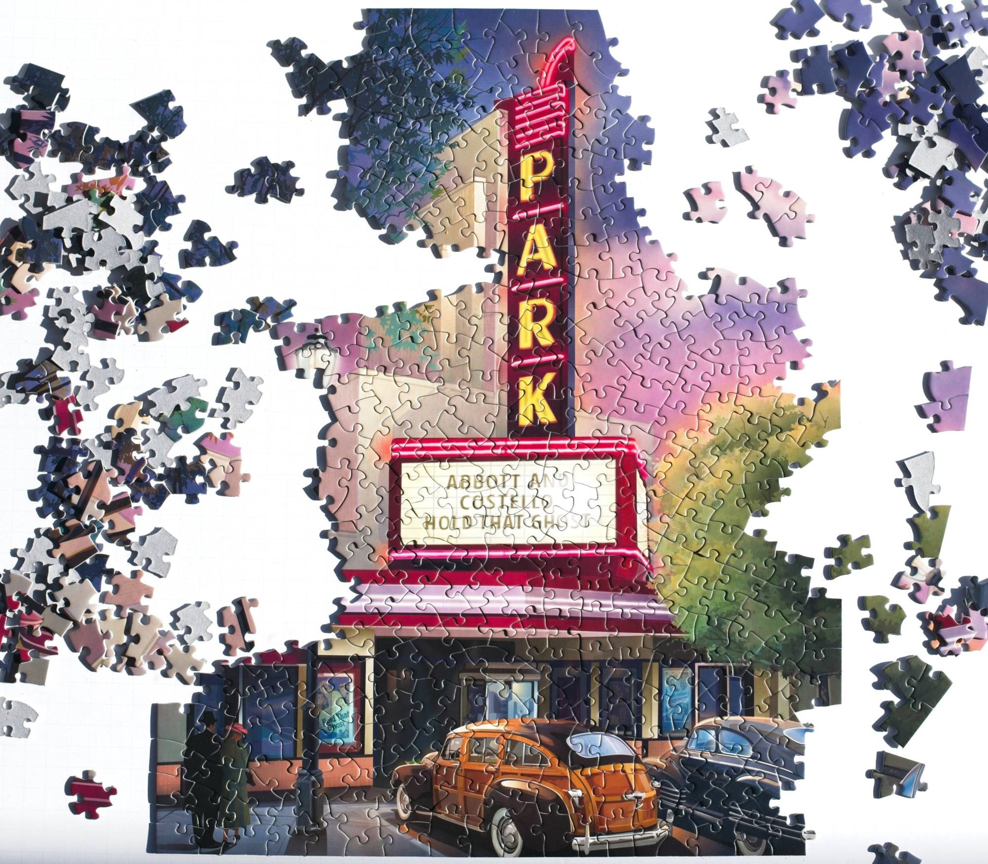 Jigsaw puzzle of a movie theater marquee with cars in front, surrounded by missing pieces.