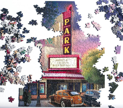 Jigsaw puzzle of a movie theater marquee with cars in front, surrounded by missing pieces.