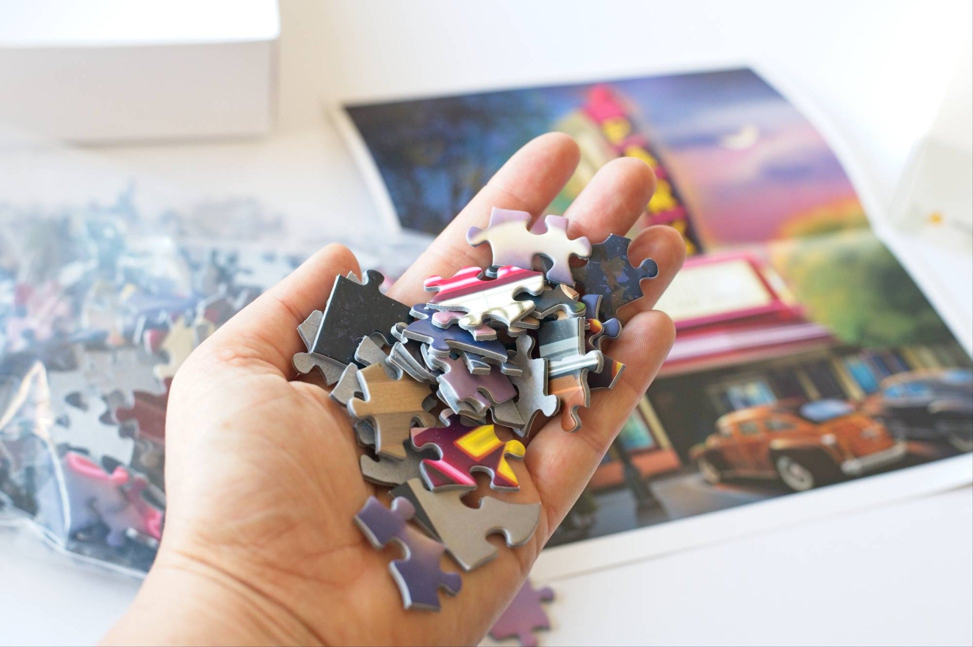 Hand holding puzzle pieces with a partially completed puzzle in the background