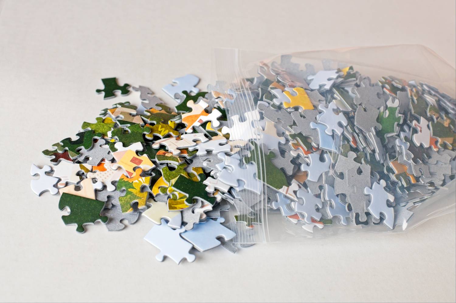 Colorful jigsaw puzzle pieces spilling out of a resealable plastic bag