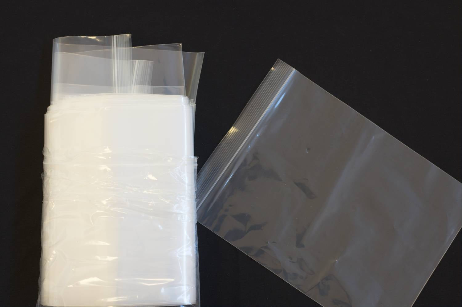 A group of resealable bags next to a single resealable bag on a black background
