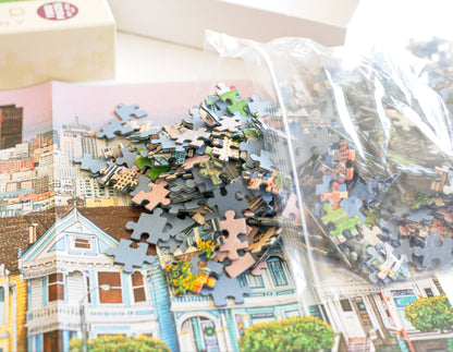 Colorful jigsaw puzzle pieces spliing out  of a resealable plastic bag onto a cityscape design next to a box.