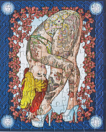 A completed jigsaw puzzle featuring a stylized illustration of a tattooed woman in a yellow and green bodysuit, bending forward while wearing white high heels. The artwork is framed by pink flowers on a blue patterned border, with circular decorative elements in the corners.