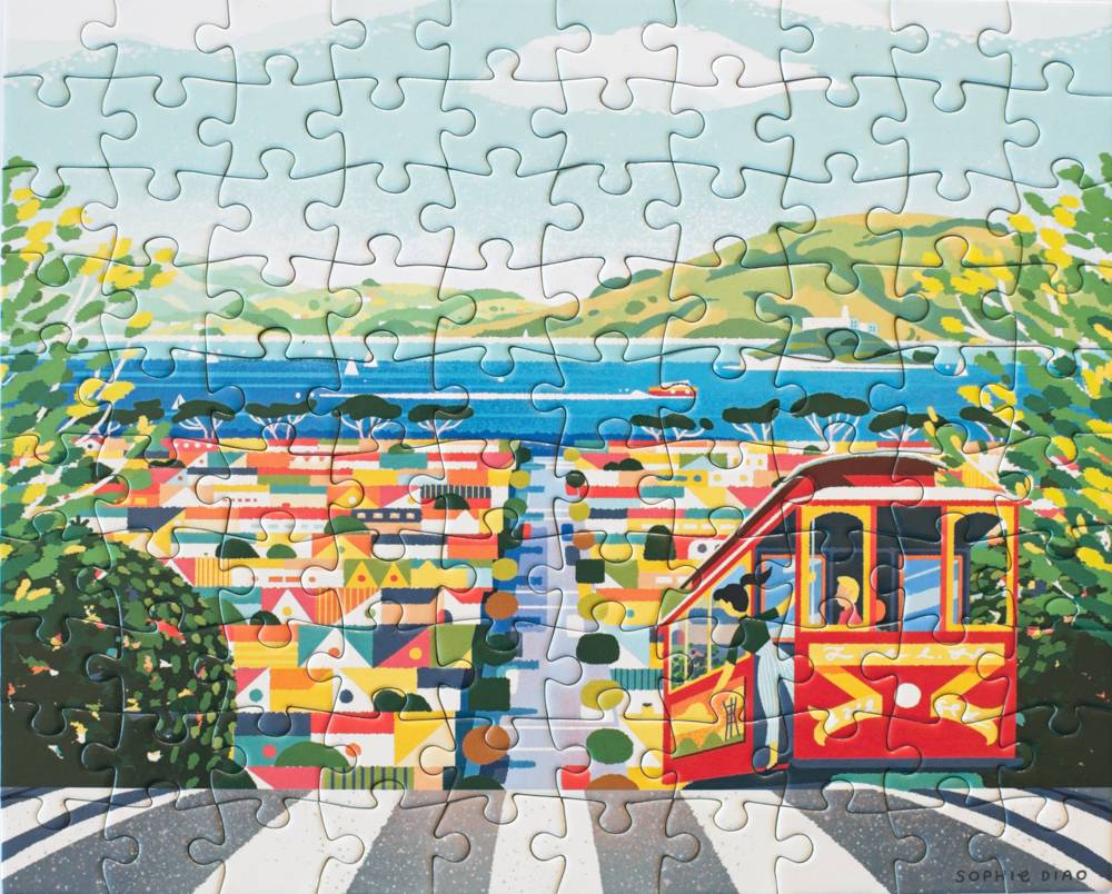 A completed jigsaw puzzle showing a colorful coastal city scene with a red cable car, blue water, green hills, and dense buildings.