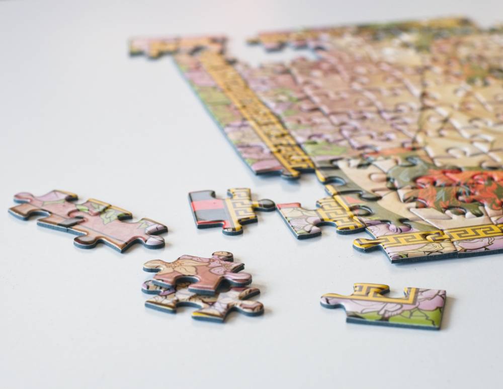 A close-up of a colorful jigsaw puzzle with several loose puzzle pieces scattered on a white surface.