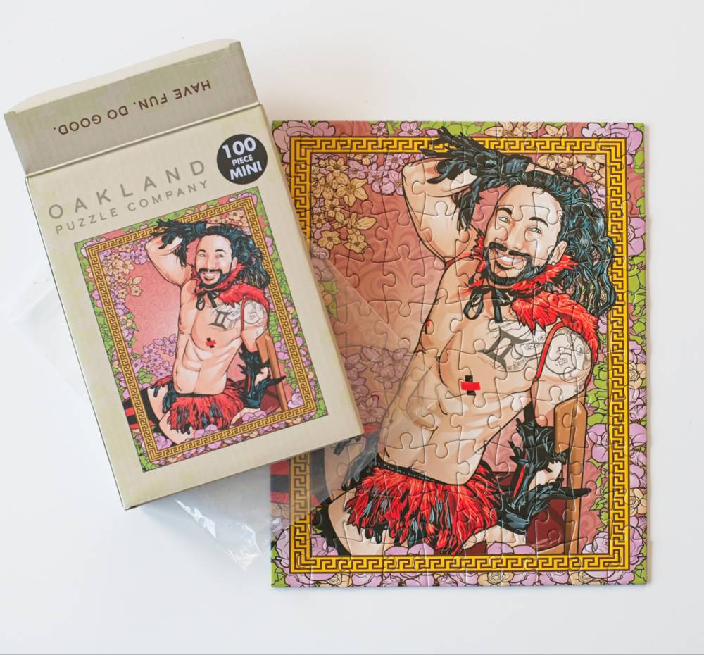 An Oakland Puzzle Company 100-piece mini puzzle shown both in its box and assembled. The puzzle features an illustration of a shirtless man with long dark hair and a red fringed skirt, with the Greek letter Pi (π) on his chest.