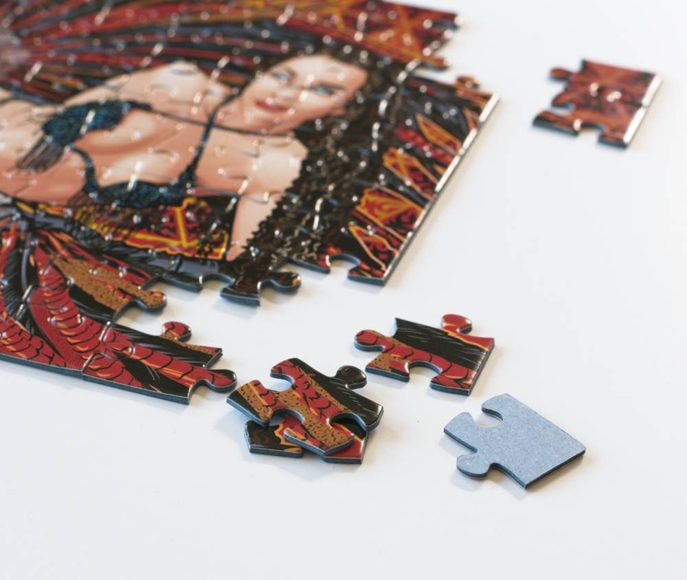 A close-up of a partially completed jigsaw puzzle showing a stylized portrait with red, black, and gold artwork, with several loose puzzle pieces scattered on a white surface.