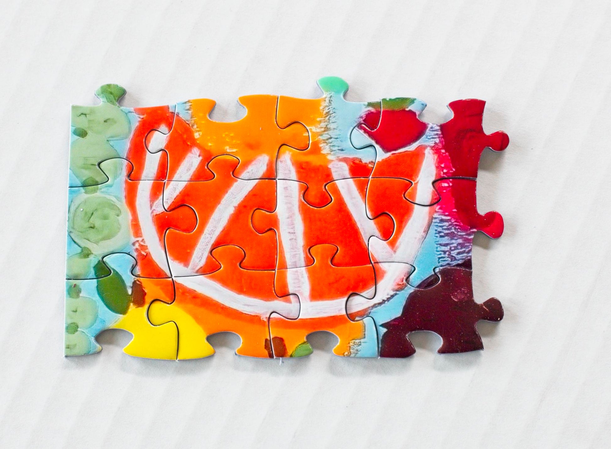 An orange wedge depicted on 12 interlinked jigsaw puzzle pieces