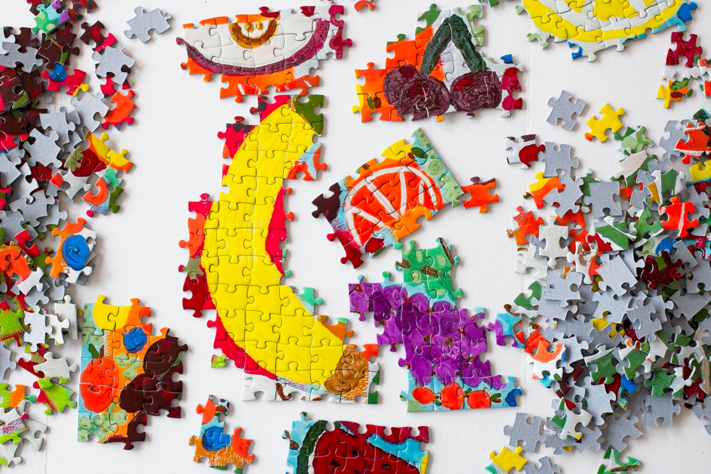 A partially assembled colorful jigsaw puzzle with a variety of fruit artistically rendered