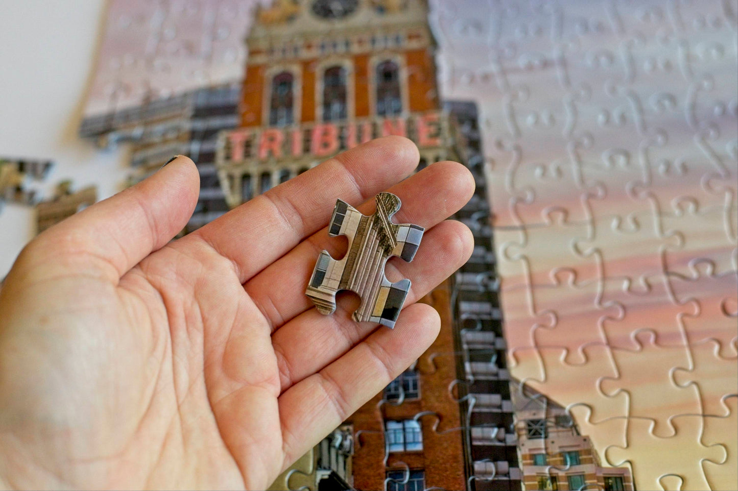 A hand holding a puzzle piece with geometric lines showing that the piece is 1.5 inches