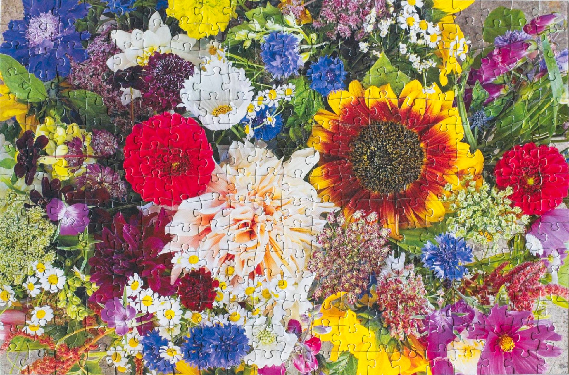 A photo of a completed jigsaw puzzle featuring a top down photo of bright floral bouquets