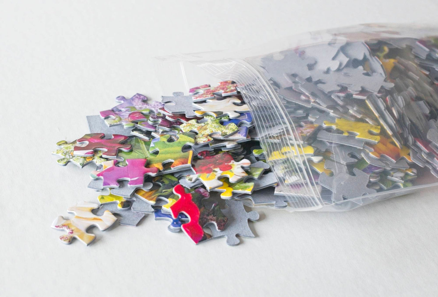 Colorful large floral puzzle pieces spilling from a resealable plastic bag