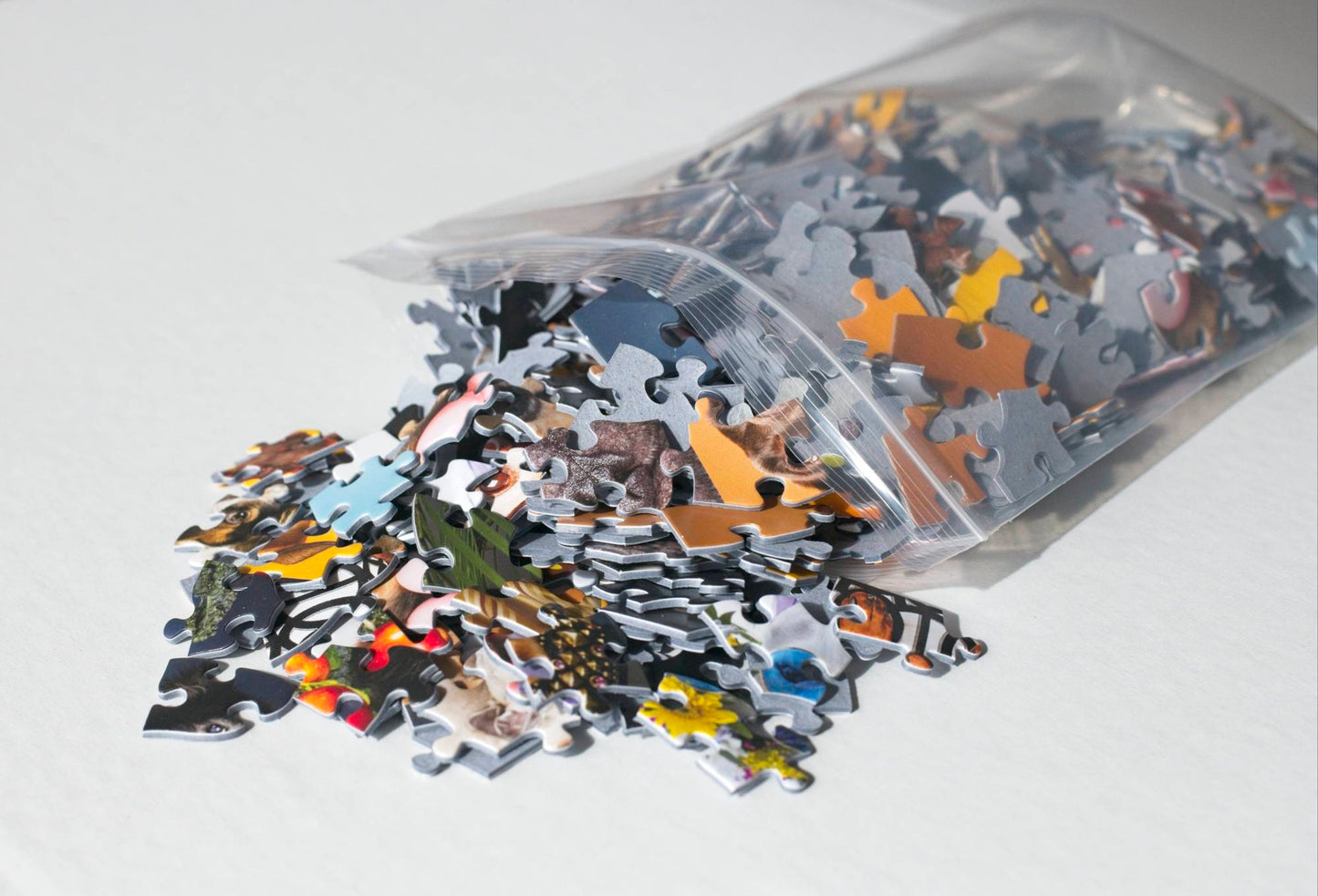 A resealable plastic bag spilling out colorful jigsaw puzzle pieces.