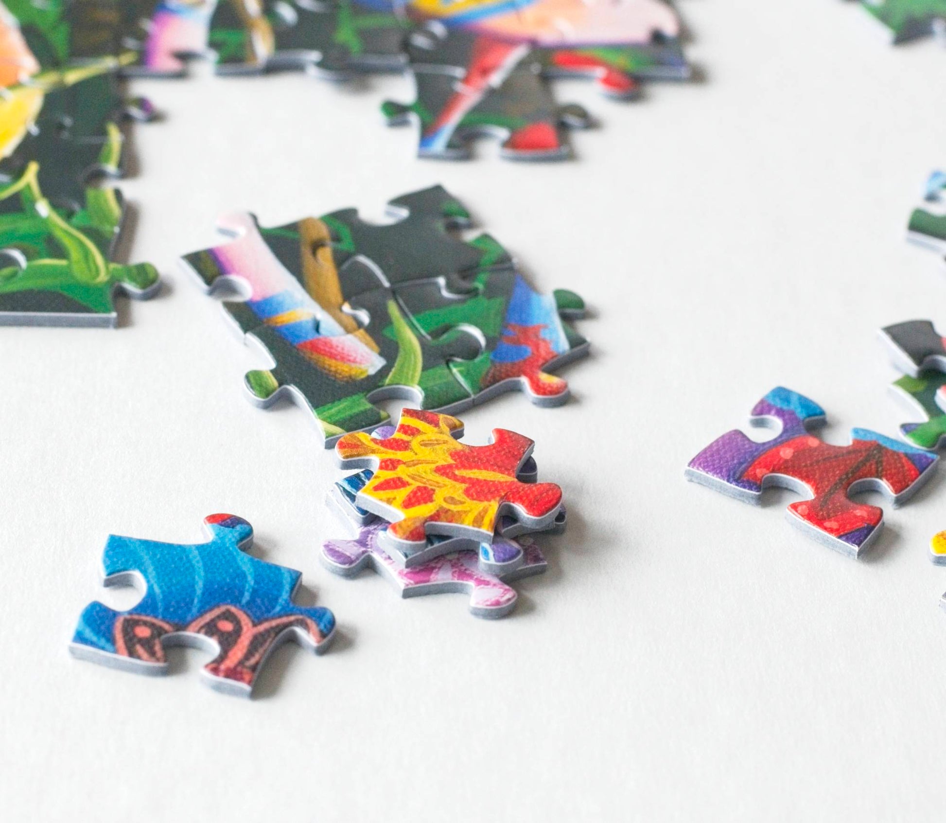 A variety of scattered, stacked, and interlinked colorful jigsaw puzzle pieces.