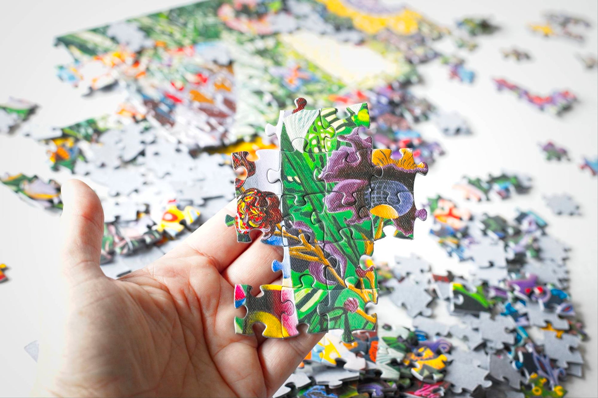 A hand holding a set of interlinked puzzle pieces that appear floral